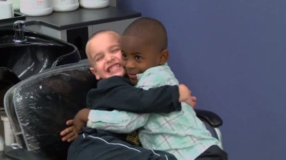 Dos niños de diferentes razas se abrazan con cariño y ríen.