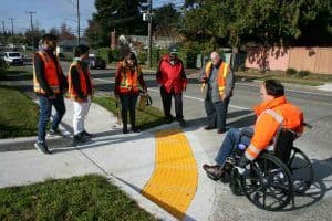 Aparece un grupo de ingenieros en la esquina de una calle en Seattle Estados Unidos, y uno de ellos está en una silla de ruedas intentando subir a la vereda.