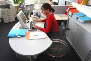 Una mujer en silla de ruedas trabajando en su escritorio
