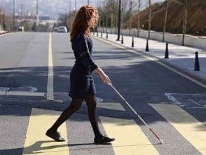 Una mujer cruzando un paso peatonal con su bastón.