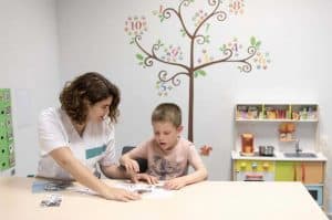 Una mujer realizando terapia a niño autista