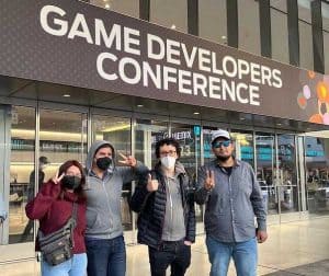 Foto de un grupo de cuatro personas de la empresa Dreams of Heaven afuera del edificio que dice Game Developers Conference en Estados Unidos.