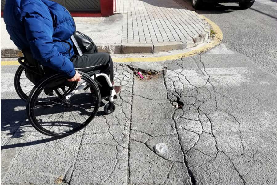 Foto de una mujer en silla de ruedas cruzando una calle en santiago.