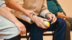 Foto de las manos de una persona con parkinson que está agarrando una pelota de terapia