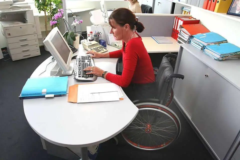 Mujer en silla de ruedas trabajando frente a un computador